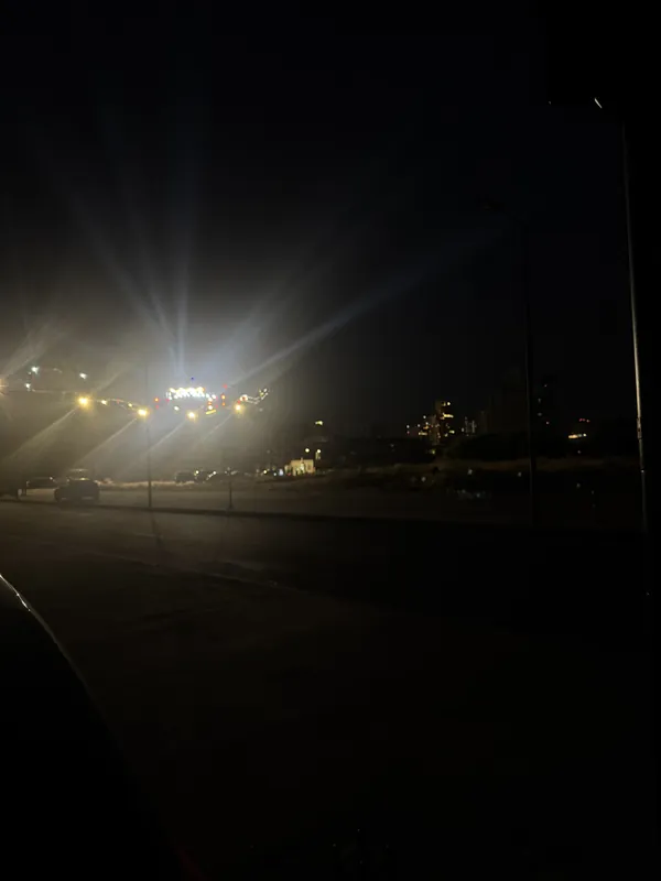 Floodlights glowing over a seafront road at night.