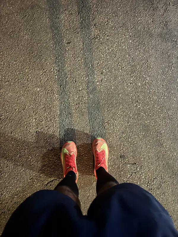 Looking down at a pair of running shoes on asphalt after a morning run.