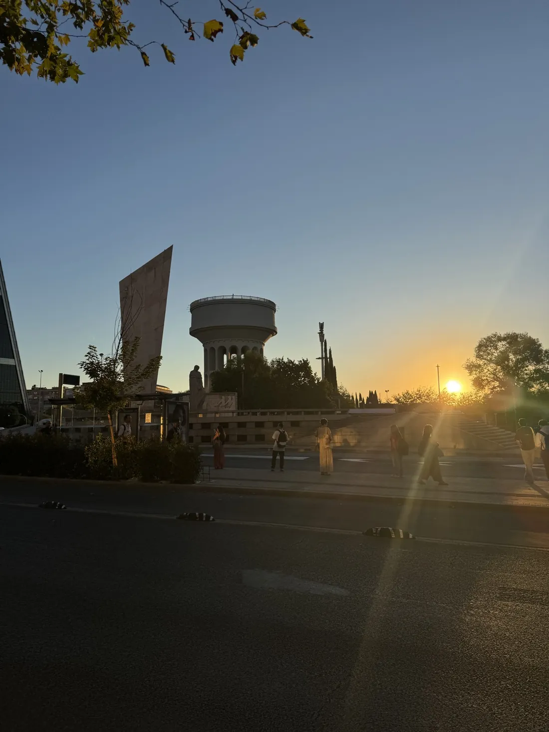 Sunrise over a wide avenue in Madrid, a few people walking in the low light.
